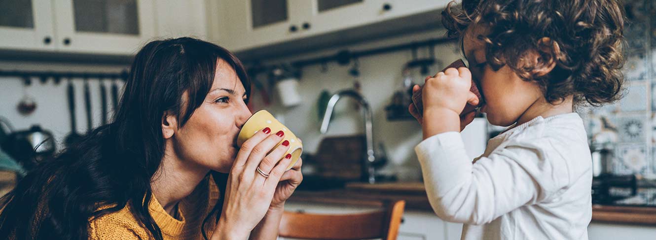 Woman having a cup of cocoa with her child in the kitchen.