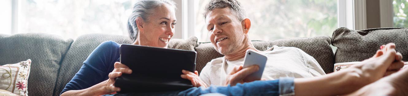 a couple sitting on a couch holding their devices