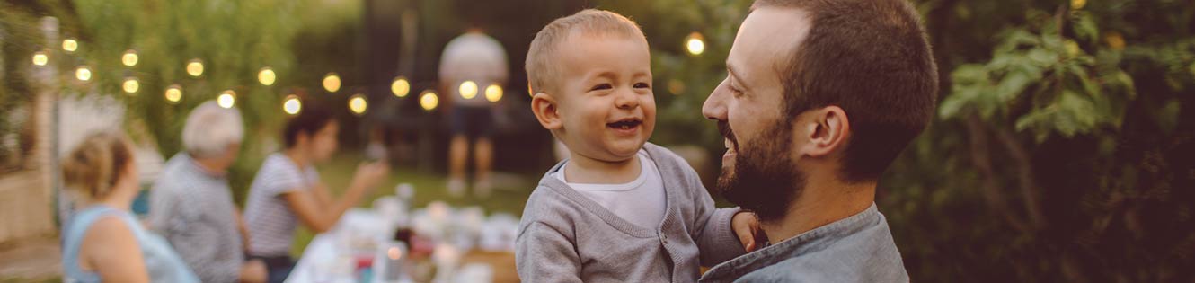 father smiling while holding his son