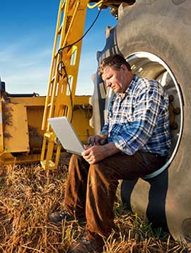 Farmer sitting in the wheel of his tractor checking his financial situation.